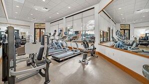 Un gimnasio con cintas de correr, máquinas de pesas y espejos.