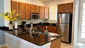 Una cocina moderna con armarios de madera, electrodomésticos de acero inoxidable, encimera de granito y un florero con flores amarillas.