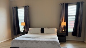 Une chambre à coucher avec un grand lit, deux tables de chevet, un tapis et des rideaux.