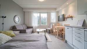Une pièce moderne et bien éclairée, comprenant un lit, un canapé, une table à manger, des chaises et un coin cuisine.