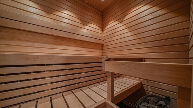 Un sauna avec des panneaux en bois et une grille métallique pour les pierres.