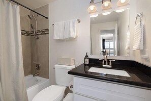 Une salle de bain moderne équipée d’une baignoire, d’une douche, de toilettes et d’un lavabo.