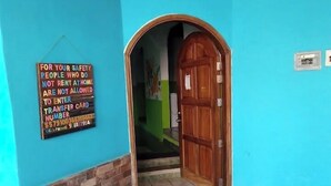 A blue-walled entrance with a wooden door and a security sign. - La Casa Del Sueño (Mazunte)