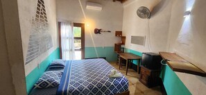 Una habitación pequeña y acogedora con cama, escritorio, silla y ventilador.