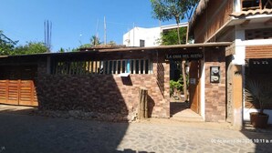 A building with a stone wall and a wooden gate, labeled "LA CASA DEL SUENO". - La Casa Del Sueño (Mazunte)
