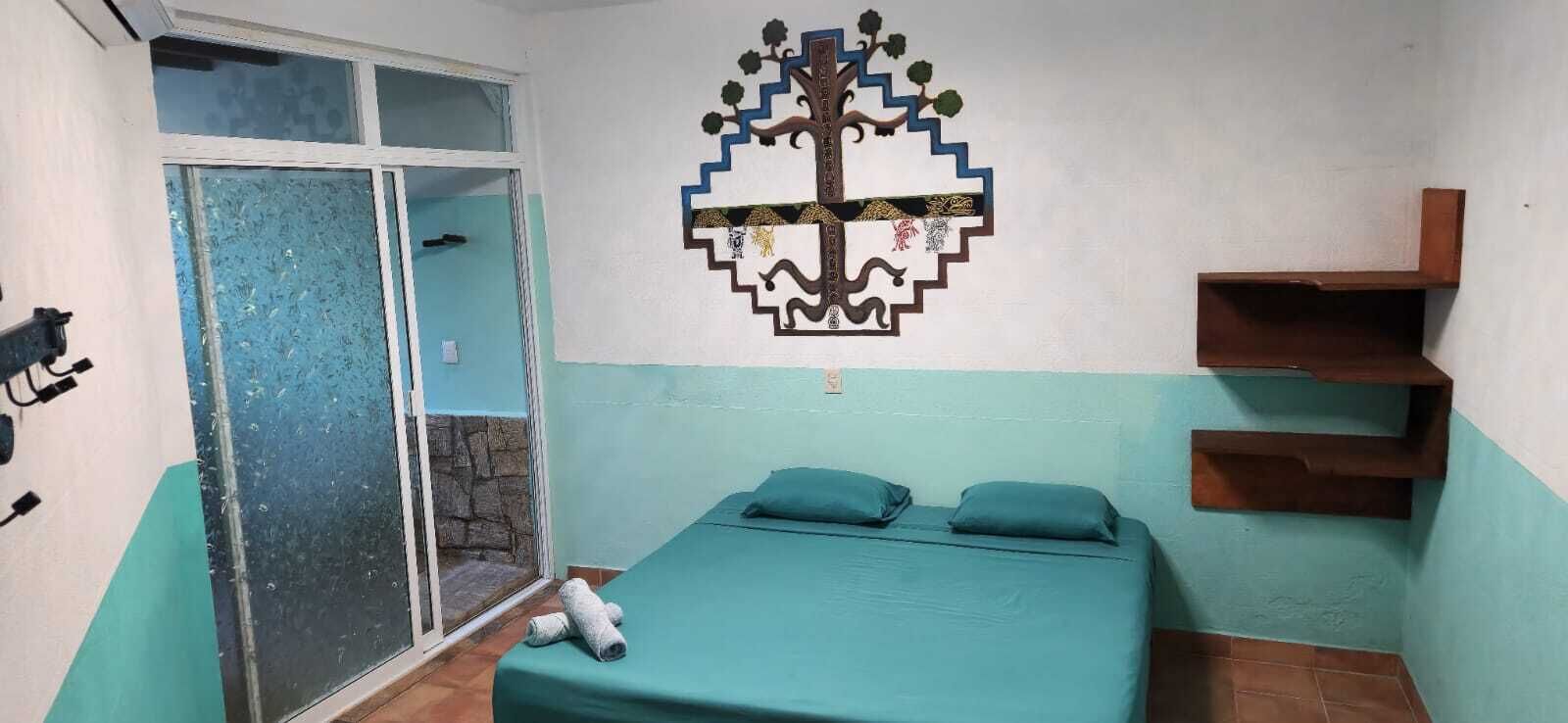 Ein Zimmer mit einem Bett, einer Wanddekoration, einer Tür und einem kleinen Holzregal.