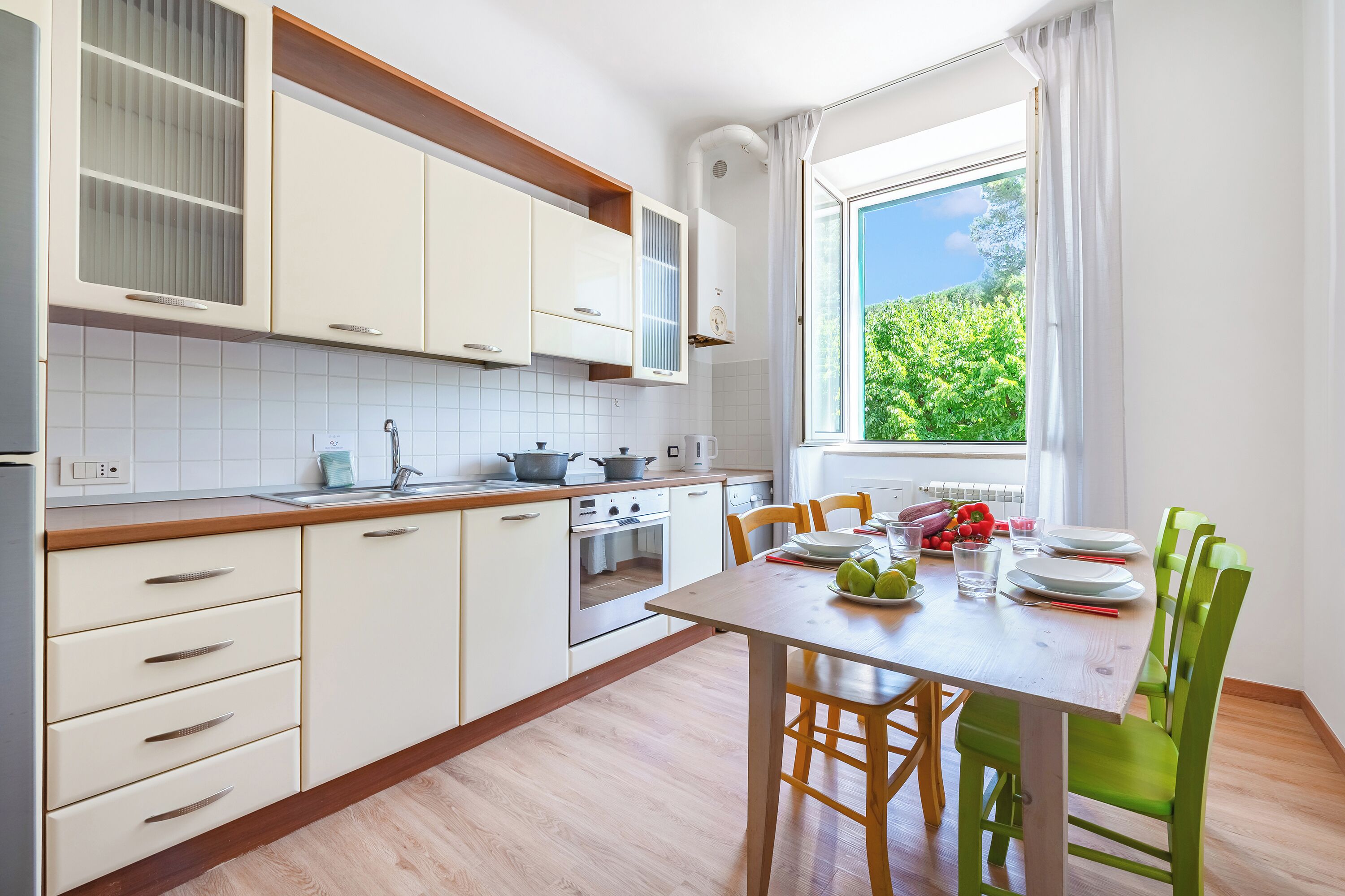 A modern kitchen with white cabinets, a wooden countertop, and a dining area with a table set for four.