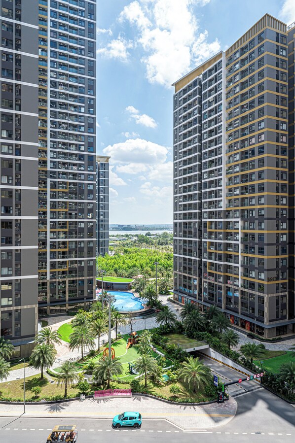 A high-rise residential building with multiple balconies, a swimming pool, and a landscaped garden area.
