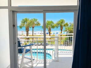 A pool area with a view of the beach, palm trees, and a sign indicating no swimming.