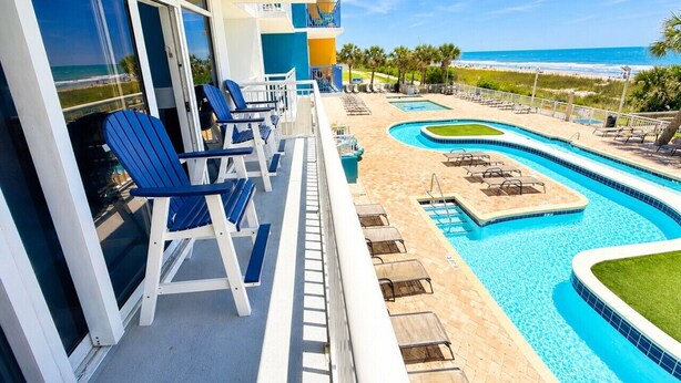 A pool area with lounge chairs, a pool, and a view of the beach. - Ocean blue Paradise, Perfect Location. (Myrtle Beach)