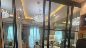A modern living room with a glass partition, wooden flooring, and a chandelier.