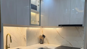 A modern kitchen with white cabinets, a black dishwasher, and a marble backsplash.