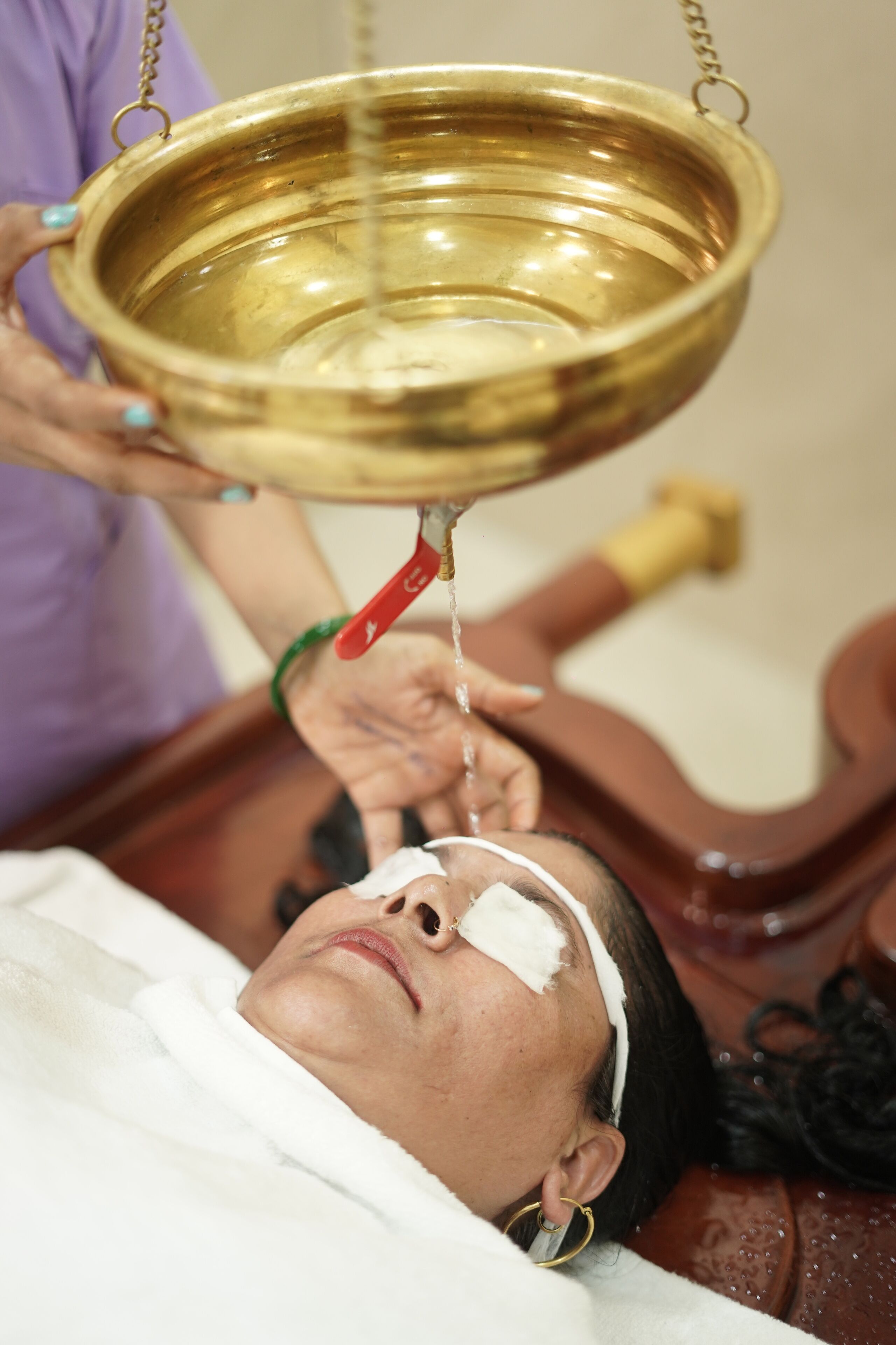 A person lying down with a golden basin above them, water flowing into it.