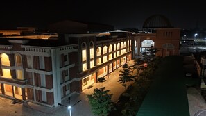 A building with multiple arches and a dome, featuring a courtyard with trees and a paved walkway. - Rishikulam Wellness Centre (Samalkha)