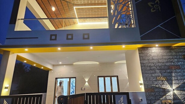 A modern building with a two-story entrance, a covered area with a wooden ceiling, and a decorative wall with a geometric pattern.