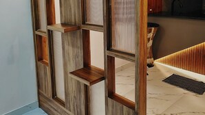 A room with a wooden partition with shelves, a marble floor, and a kitchen area with a sink and countertop.