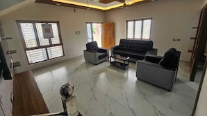 A spacious living room with a modern design, featuring a sofa set, a coffee table, and a decorative floor lamp.