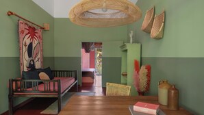 A room with a wooden bed, a dining table with a book, a hanging light fixture, and a view of another room. - Casa Tikiri - BOUTIQUE HOTEL Adults-Only (Ahangama)
