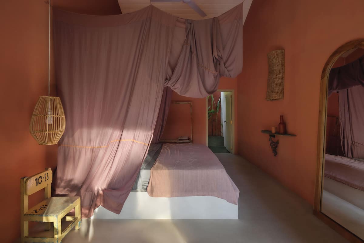 Una habitación con cama, una silla y un dosel colgante.