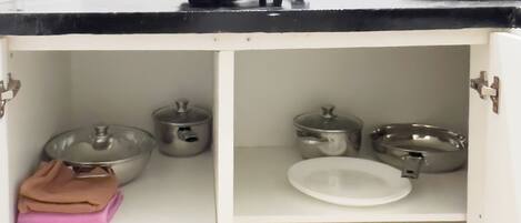 A kitchen with white cabinets, a black countertop, and various kitchen utensils and cookware.