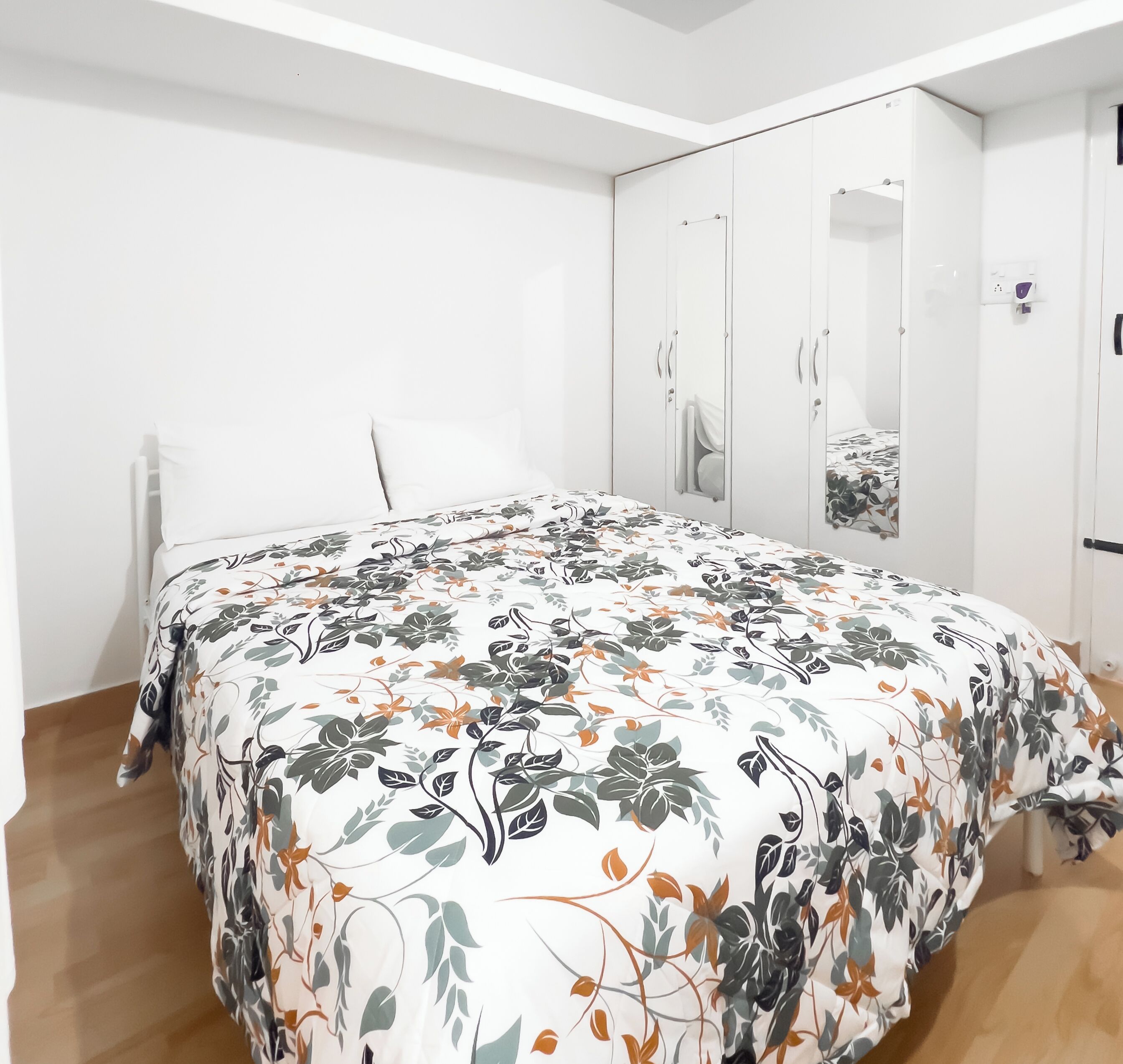 A bedroom with a bed, a wardrobe, and a mirror.