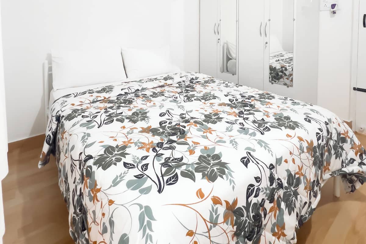 Un dormitorio con cama, armario y espejo.