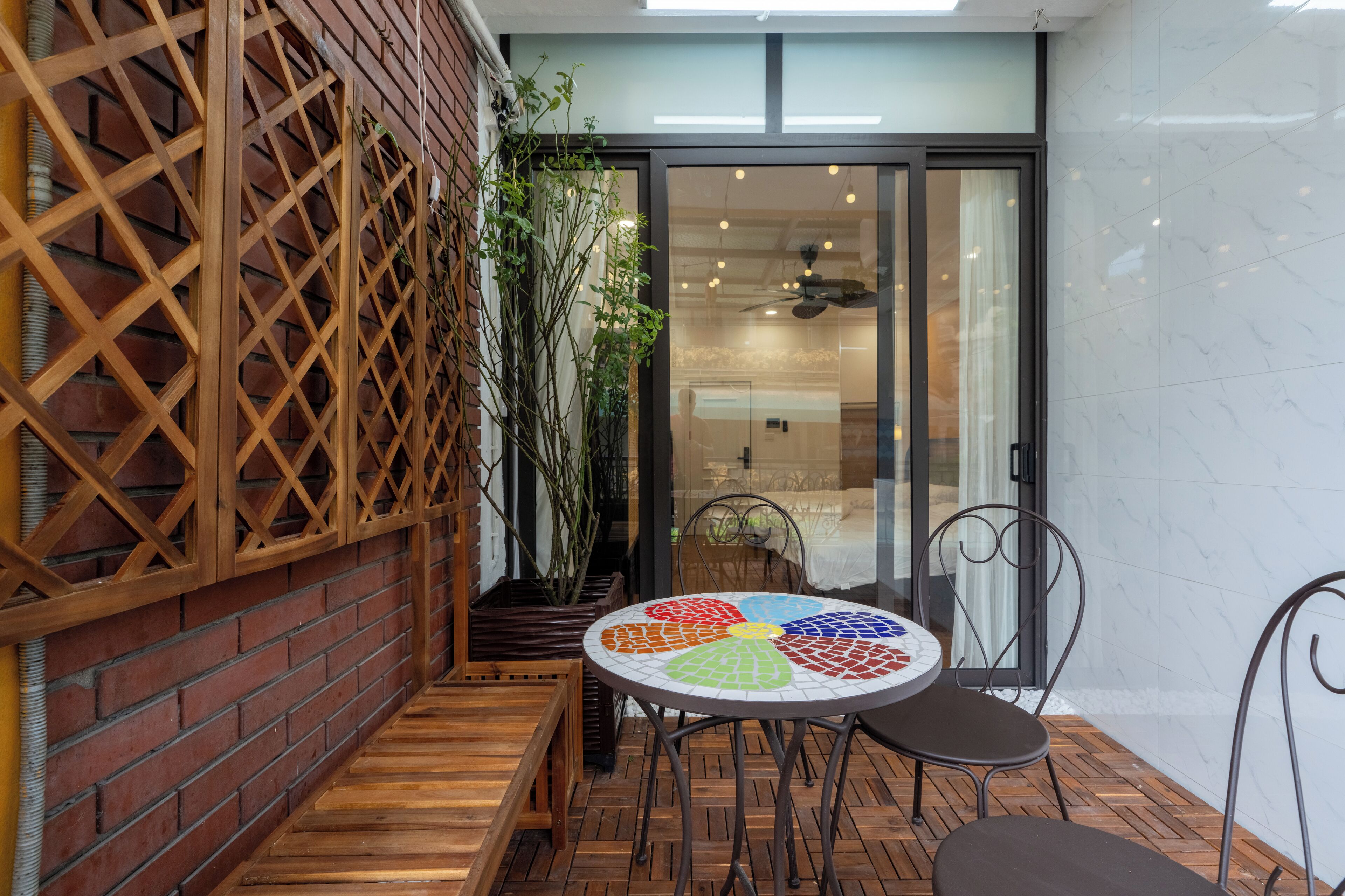 A patio with a mosaic table, wooden benches, and a lattice wall.