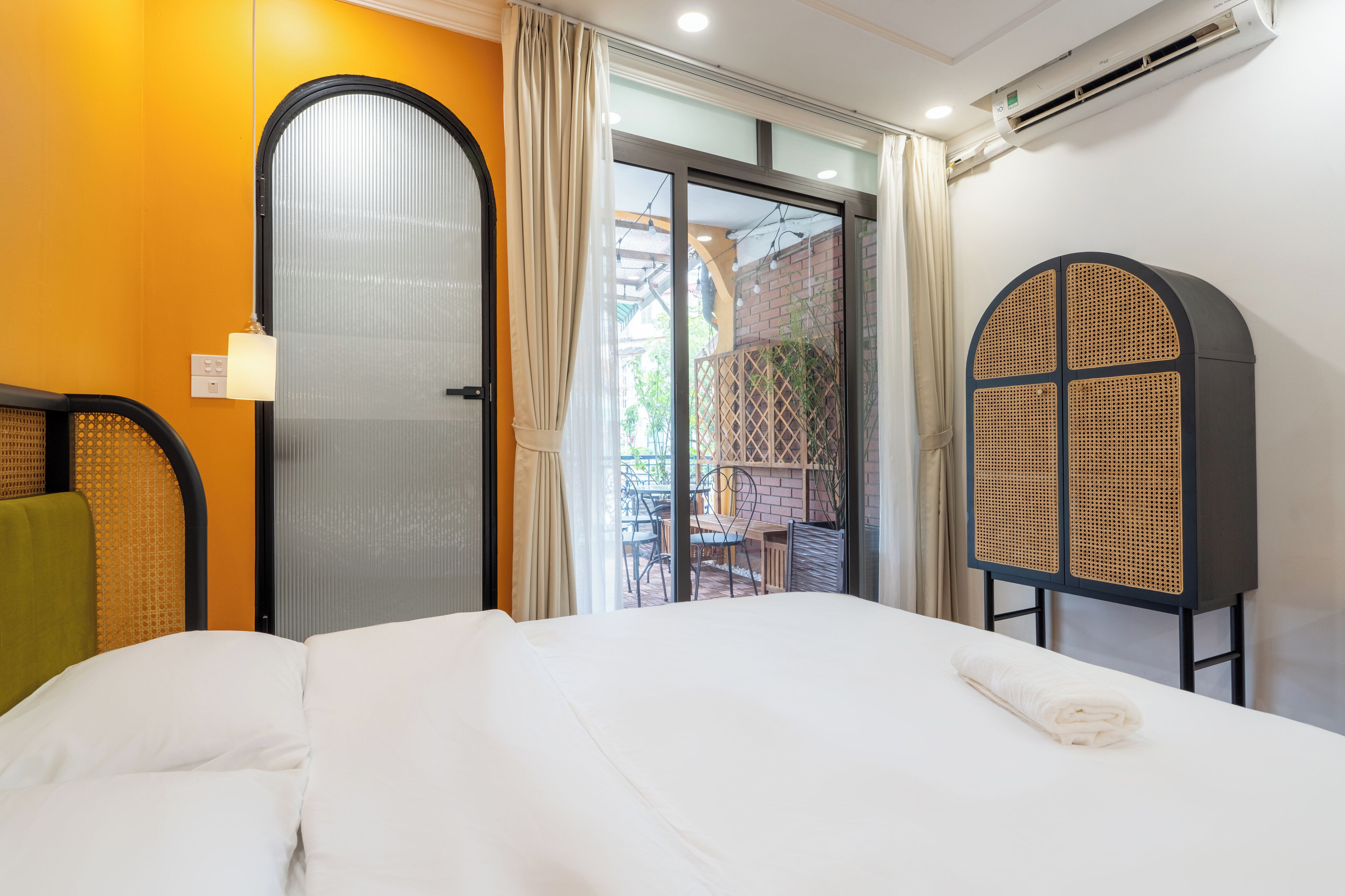 Een hotelkamer met een bed, een raam met gordijnen, een airconditioning en uitzicht op buiten.