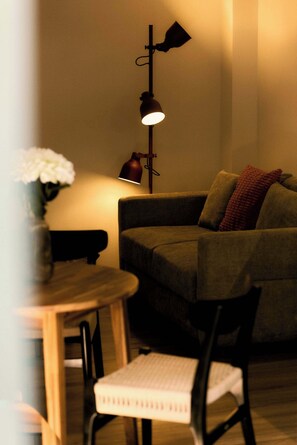 A cozy living room with a sofa, a table with a vase of flowers, and a floor lamp.