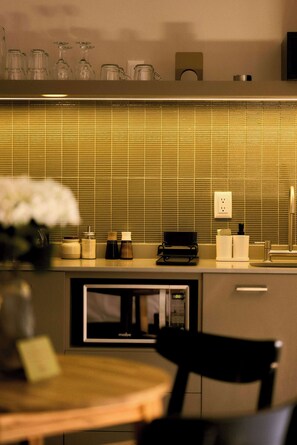 Une cuisine moderne équipée d’un four à micro-ondes encastré, d’un évier et d’un plan de travail sur lequel sont disposés divers ustensiles de cuisine.