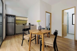 A modern kitchen with a built-in refrigerator, a dining table with four chairs, and a vase with flowers.