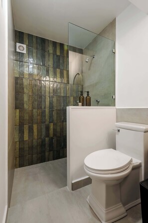 A bathroom with a toilet, a shower, and a tiled wall. - Zaterra: A Tranquil Oasis in Roma Norte. (Ciudad de México)