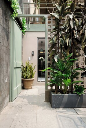 A modern building entrance with a concrete floor, a green door, and potted plants.