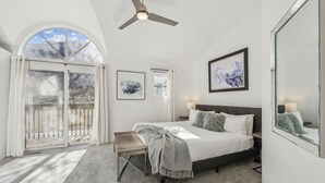 Ein Schlafzimmer mit Bett, einer Bank, einem Deckenventilator und einem großen Fenster.