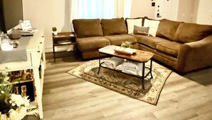 Un salon avec un canapé, une table basse, un téléviseur et un ventilateur de plafond.