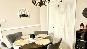 Un coin repas avec une table en bois foncé, des chaises grises et un lustre.
