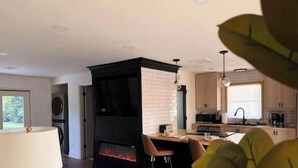 Una cocina moderna con chimenea integrada, armarios de madera y un comedor con una silla.