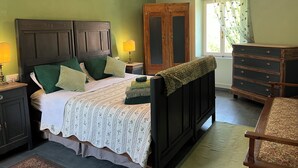 Ein Schlafzimmer mit Bett, Nachttischen, einem Schminktisch und einem Fenster mit Vorhängen.