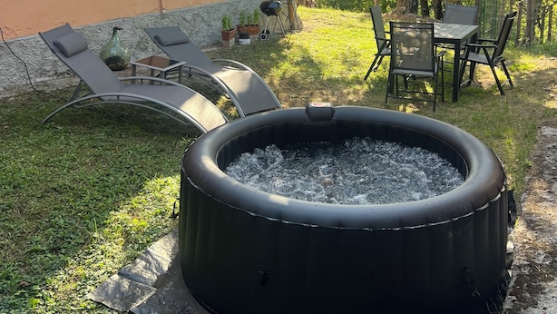 Un patio trasero con jacuzzi, mobiliario exterior y una zona de terraza.