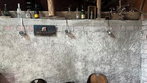 Un rústico espacio de bar con sillas de madera, un barril de madera y varias botellas en un estante.