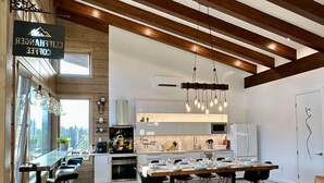 A modern kitchen with a central island, bar seating, and a dining area with a large table. - Luxury Alpine Retreat - Hot Tub & Sauna - Sleeps 16 - Cliffhanger Chalet (Comox Valley C (Puntledge-B*)