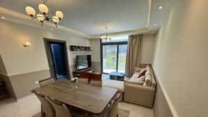 A modern living room with a dining area, a sofa, a TV, and a balcony with a view. - Cool 2-bedroom apartment with AC in Cairo Governorate (Cairo Governorate)