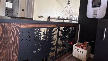 Una cucina con isola in legno, un armadietto nero e un cesto con l'etichetta 'TOYS'.