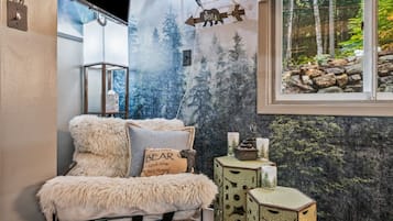 Een gezellige kamer met een fauteuil met bont, een kussen met beerprint en een decor kast met kaarsen.