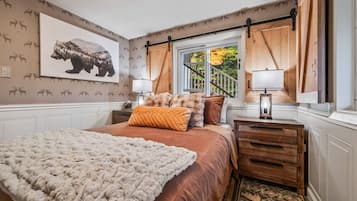 Unwind in our cozy Queen bedroom featuring warm rust-colored bedding, a chunky knit throw, rustic barn doors, and woodland-inspired décor. A peaceful retreat after a day of hiking, skiing, or exploring the White Mountains.