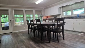 Un coin repas avec une table et des chaises en bois foncé, des meubles blancs et une fenêtre donnant sur un paysage verdoyant.