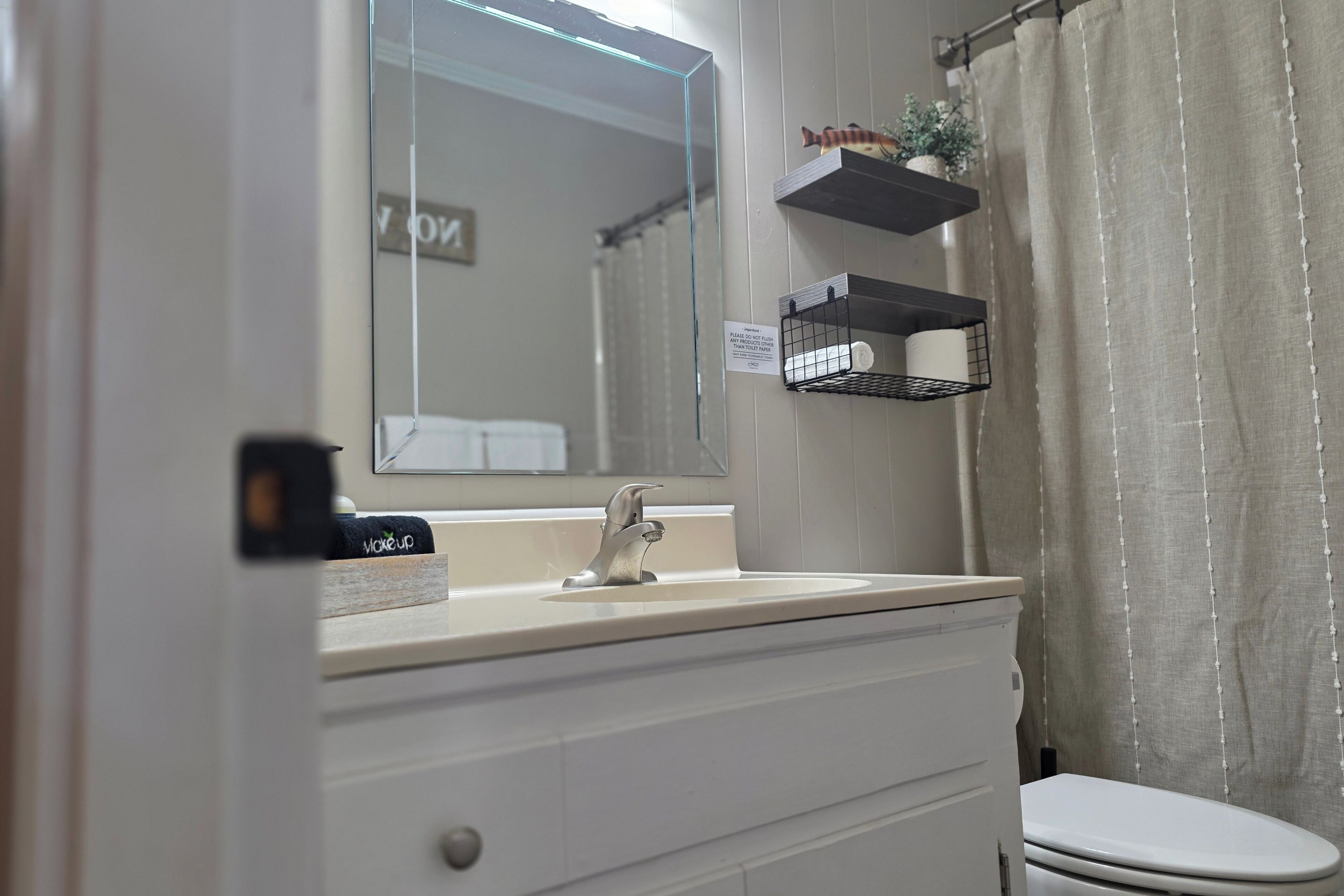 Une salle de bain avec un lavabo blanc, un miroir, un distributeur de serviettes et des toilettes.