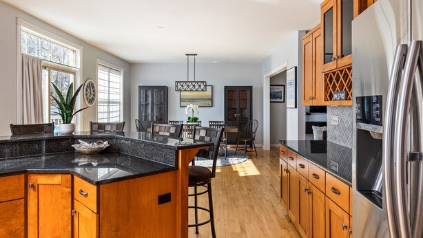 A modern kitchen with wooden cabinets, a granite countertop, and stainless steel appliances.