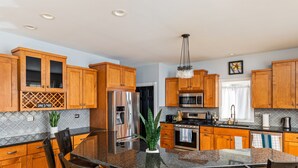 A modern kitchen with wooden cabinets, stainless steel appliances, and a granite countertop.