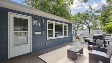 A house with a 'WELCOME' sign, number 201, and a deck with outdoor furniture.